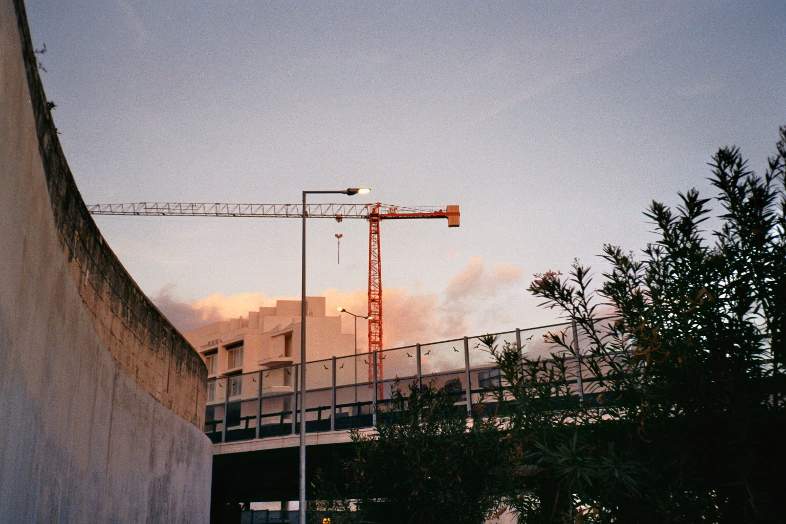 Roter Baukran hinter einer Straßenbrücke bei Abenddämmerung auf Malta.